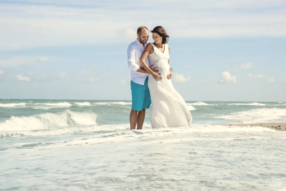 Séance grossesse sur une plage, face aux vagues.